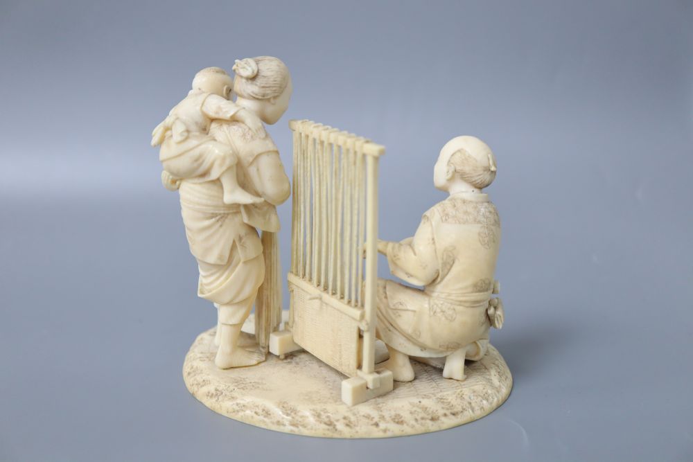 A Meiji ivory okimono of a lady carrying a child and man beside a weaving loom, height 12cm